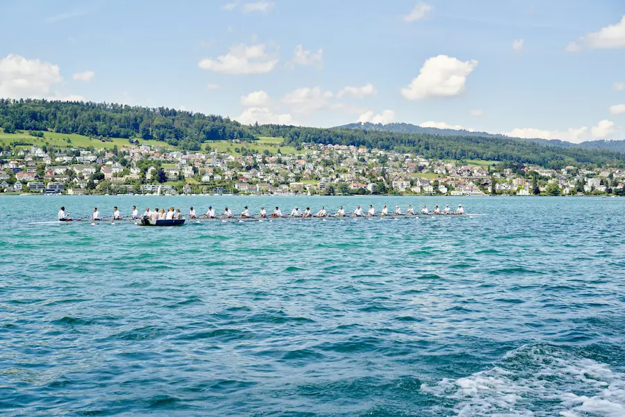 Rowing regatta on Lake Zurich with a lakeside Swiss town and green hills in the background