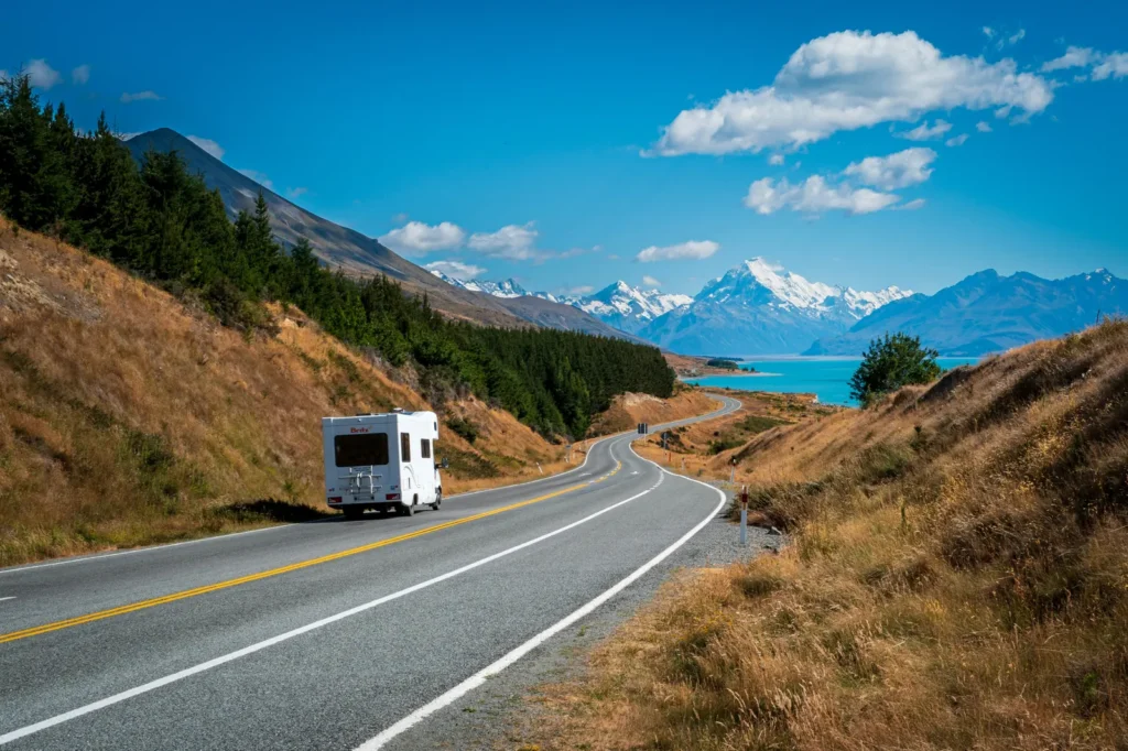 Campervan driving beside turquoise Lake Pukaki with Aoraki/Mount Cook in the distance