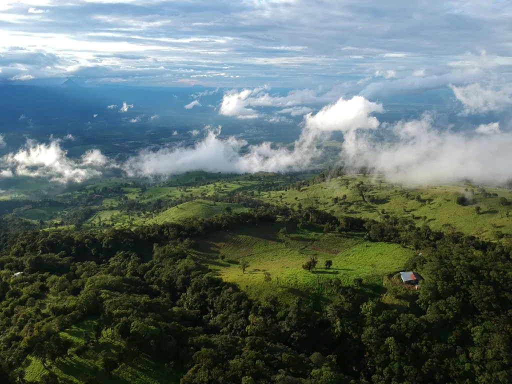 Aerial view of Costa Rica's central mountain range with clouds spilling over green highland ridges, dividing the Pacific and Caribbean climate zones