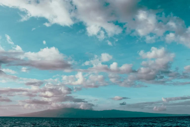 Cloudy sky over the ocean with a Hawaiian island silhouette in the distance
