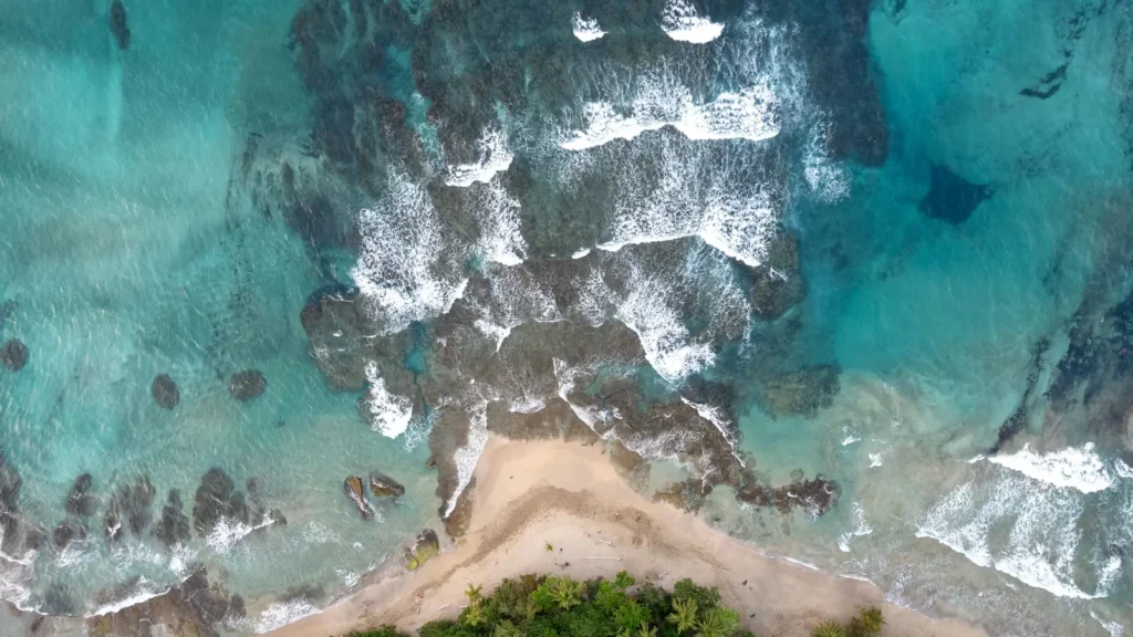 Aerial view of a rocky Costa Rica coastline where dense green rainforest meets turquoise Pacific waves