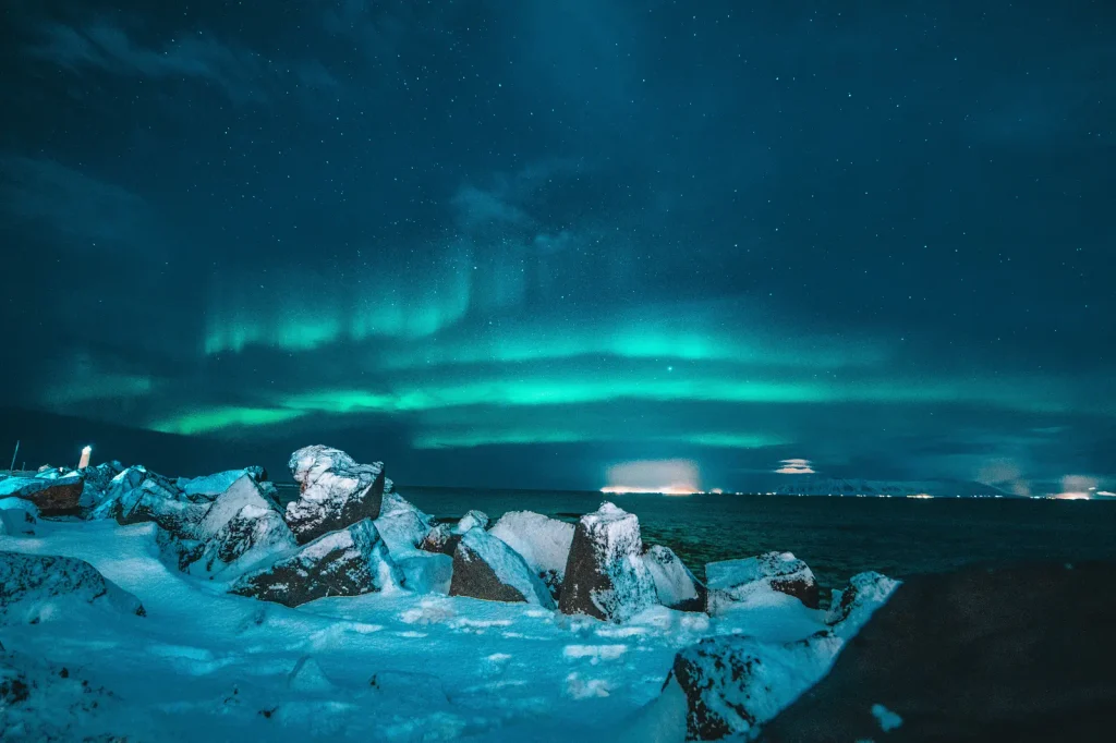 Green northern lights over a snowy Icelandic coastline at night