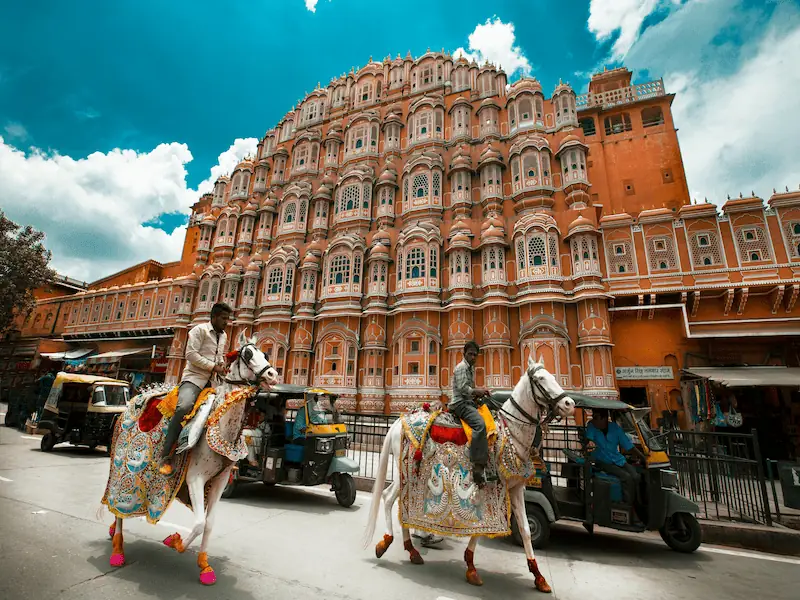 "Hawa Mahal, the Palace of Winds, in Jaipur, Rajasthan, with decorated horses passing in front