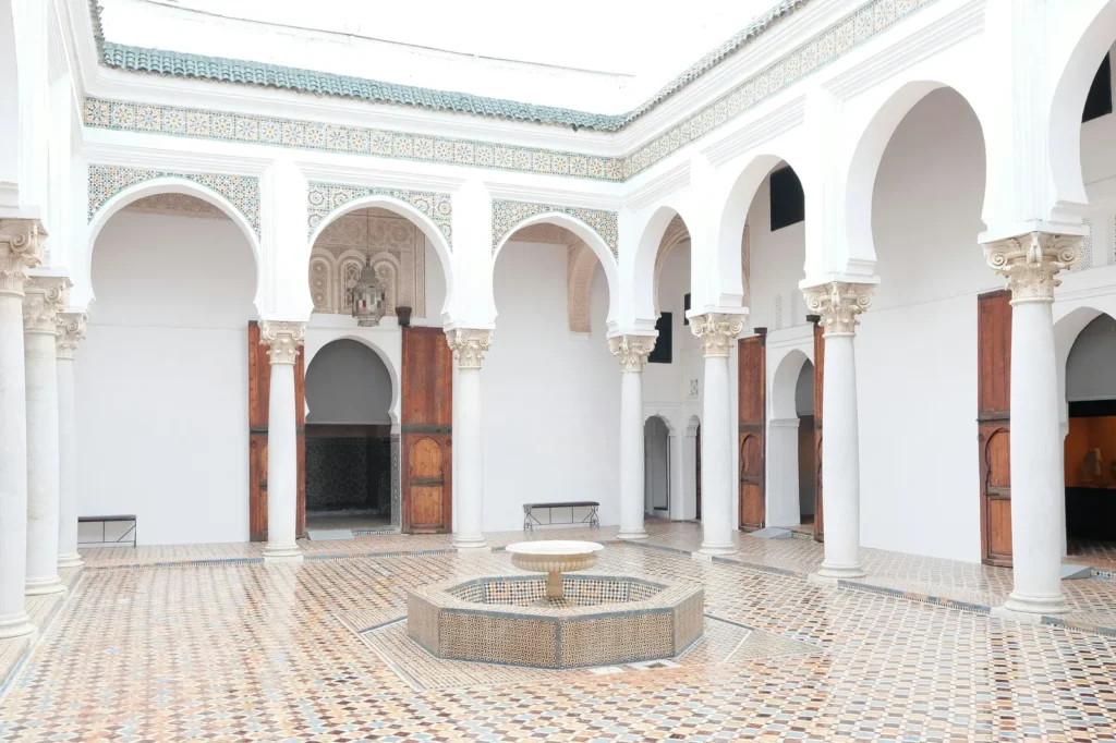 Traditional Moroccan riad courtyard with tiled fountain and horseshoe arches in Marrakech