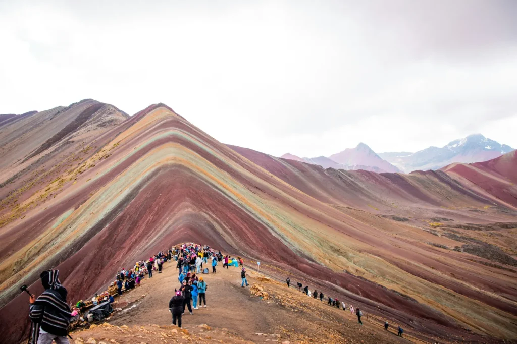 Tourists walking along the striped slopes of Rainbow Mountain (Vinicunca), Peru