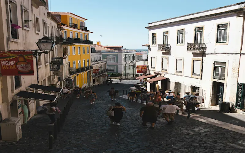 Crowded cobblestone street in Lisbon's old town during peak season