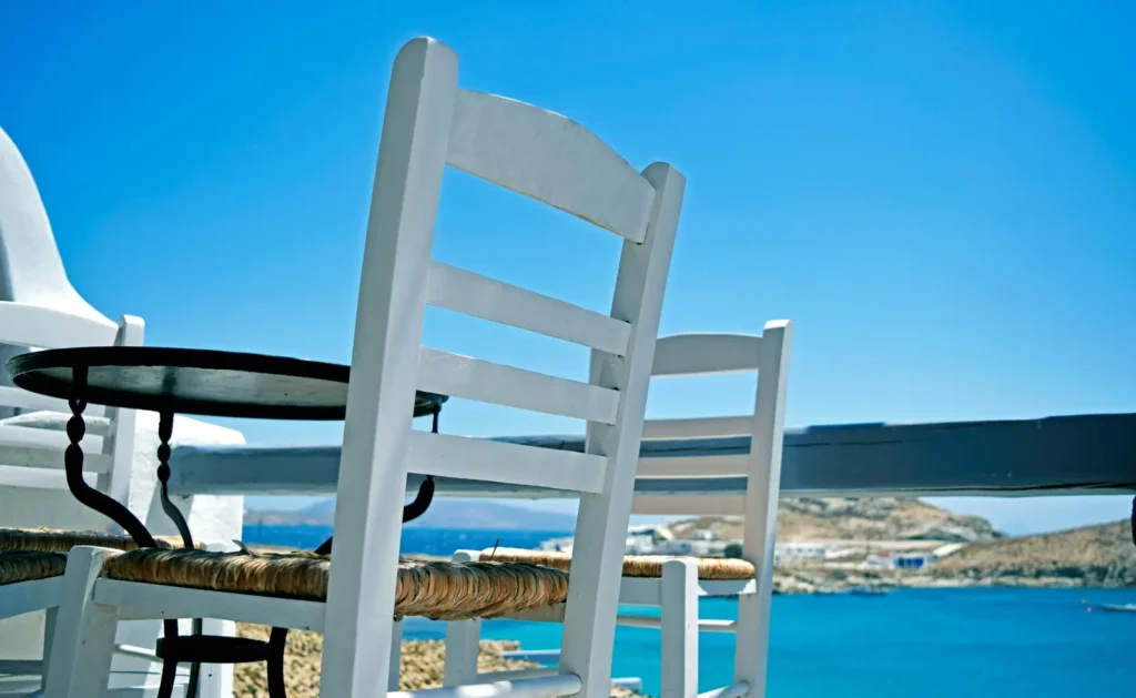 White chairs on a terrace overlooking the sea in the Cyclades