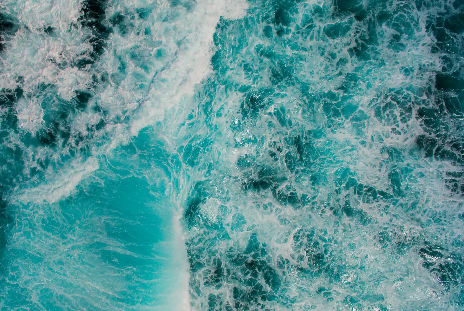 Aerial view of turquoise waves breaking into whitewater