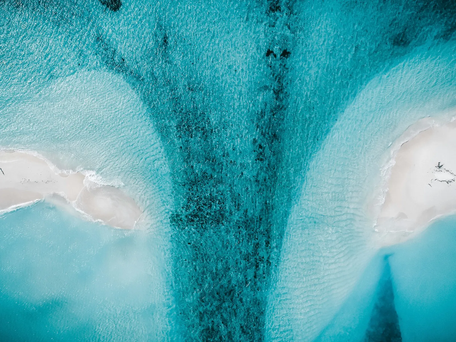 Aerial view of white sandbanks and a deep channel in turquoise Maldives water