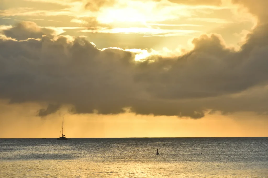 Dramatic sunset clouds over the ocean in Mauritius with a sailboat silhouette
