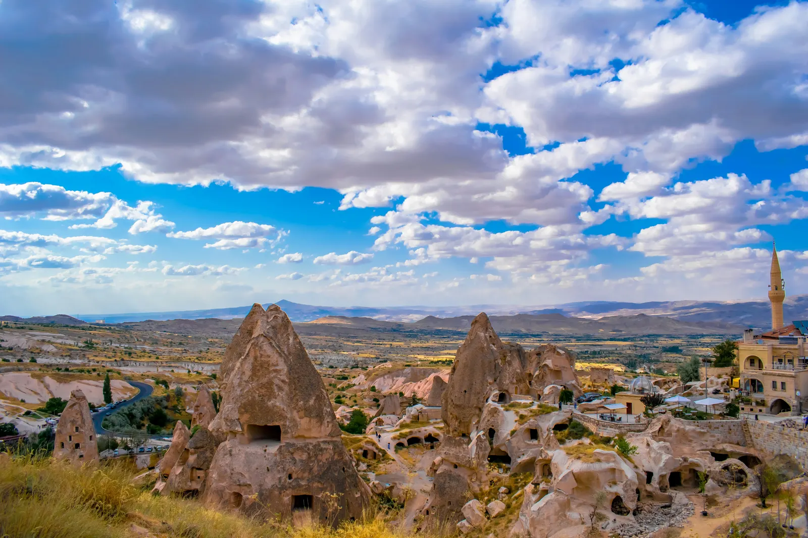 Wide landscape of Göreme's fairy chimneys and cave dwellings under a cloud-filled sky