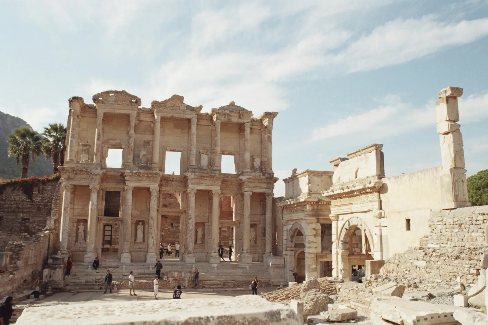 The two-story marble facade of the Library of Celsus at Ephesus, with visitors on the steps below