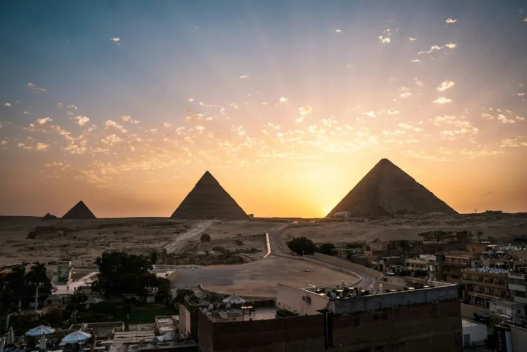 The Giza pyramids and Sphinx silhouetted against a golden sky over Cairo, Egypt