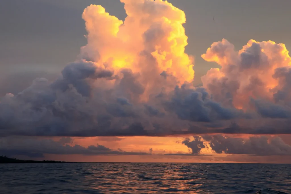 Towering storm clouds lit orange at sunset over the ocean off Fiji