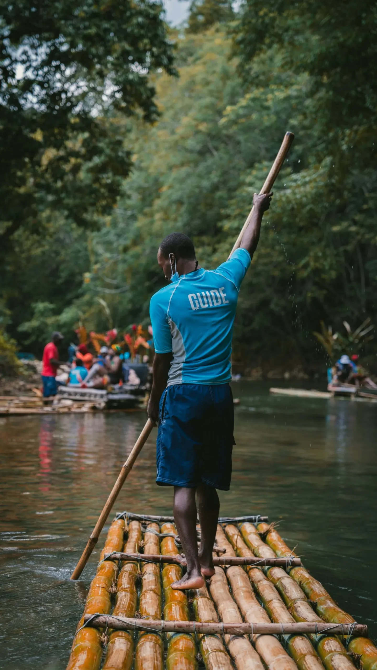 Guide poling a bamboo raft down a river in Jamaica